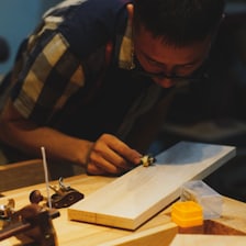 Un artisan travaille une pièce de bois à l'établi.